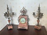 trois horloges posées sur une table sur laquelle se trouvent trois bougies