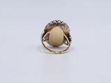 a gold ring with an oval stone surrounded by a flower