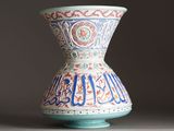 a vase with arabic writing on it sitting on a table