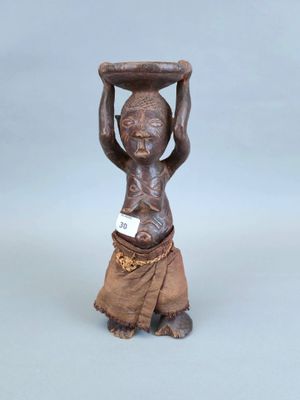 une petite statue représentant un homme tenant un bol sur la tête