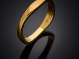 a gold wedding ring with a curved design on a black background