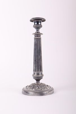 une bougie argentée posée sur une table blanche