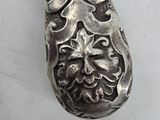 a silver spoon with a design on it on a white surface