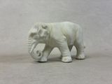 un petit éléphant blanc posé sur une surface blanche