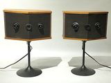 pair of speakers on stands with wires attached to them on a white surface