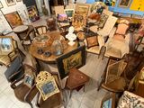 de nombreuses chaises et tables dans une pièce où sont accrochés des tableaux aux murs