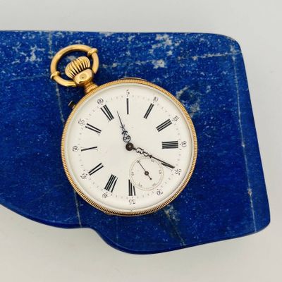 a gold pocket watch with roman numerals on it
