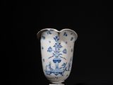 blue and white vase on a black surface with a black background