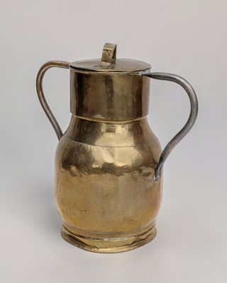 an antique brass pitcher with a handle on a white background