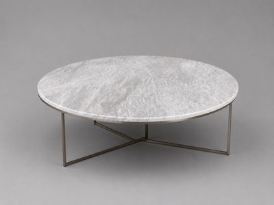 une table basse en marbre blanc avec un piètement en métal, sur fond gris
