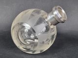 un vase en verre transparent muni d'une poignée argentée sur un fond noir