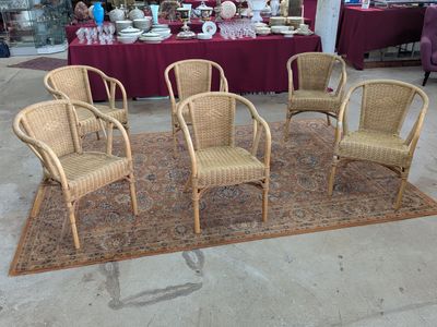 plusieurs chaises en osier et un tapis dans une pièce où se trouve une table rouge