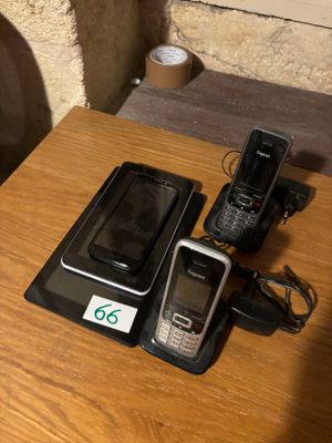 trois téléphones portables posés sur une table à côté d'un chargeur