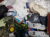 a pile of shoes and books on a bed