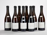 six bouteilles de vin sont alignées sur une surface blanche