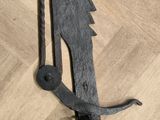 a metal object on a wooden floor that looks like a dragon