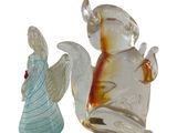 two glass figurines of angels sitting next to each other