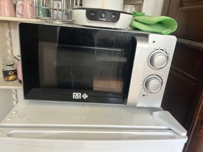 a microwave sitting on top of a refrigerator in a kitchen