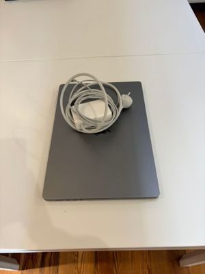 a white table with a laptop and a charger on it