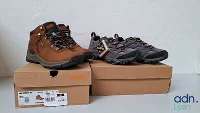 deux paires de chaussures de randonnée posées sur des cartons, sur une table
