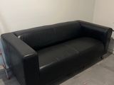 a black leather couch sitting in a corner of a room