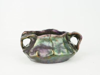 a purple and green vase with handles on a white surface