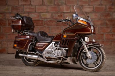 a brown motorcycle parked in front of a brick wall