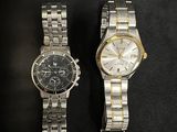 two watches sitting side by side on a black surface