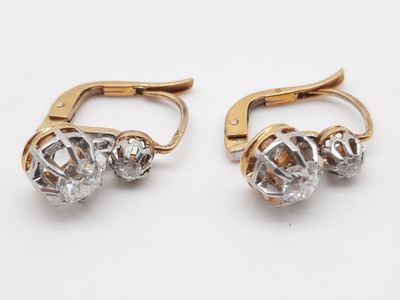 deux paires de boucles d'oreilles en or et en cristal posées sur un fond blanc