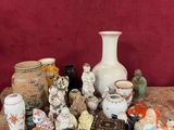 de nombreux vases de toutes sortes posés sur une table, avec un mur rouge en arrière-plan