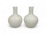 une paire de vases blancs posés l'un sur l'autre sur une surface blanche
