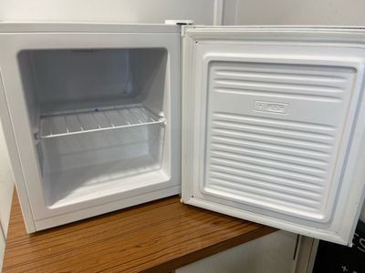 a small white refrigerator with its door open on a wooden counter
