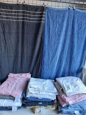 many folded towels on a shelf next to a shower curtain