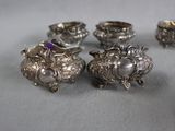 four silver dishes with purple stones on top of them on a gray surface