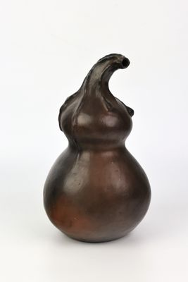 un vase brun posé sur une surface blanche