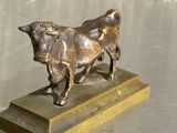 statue en bronze représentant un taureau, posée sur un socle en bois, elle-même posée sur une table