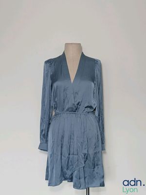 La robe est bleue, elle a des manches longues et un col en V.