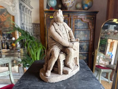a statue of a man sitting on a chair in a room
