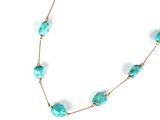 a close up of a necklace with turquoise beads on a white background