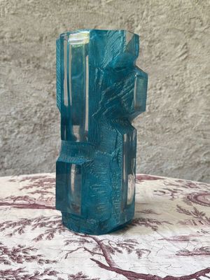 un vase en verre bleu posé sur une table recouverte d'une nappe rouge et blanche