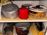 de nombreuses casseroles et poêles posées sur une étagère dans la cuisine