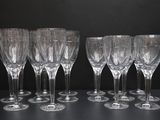 six verres à vin vides alignés sur une table, sur fond noir