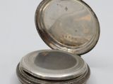 a silver pocket watch sitting on top of a white table