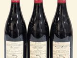 three bottles of red wine sitting next to each other on a table