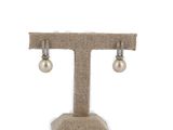 pearl and diamond earrings on a stand on a white background