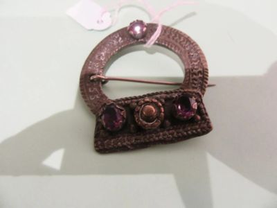 a brown brooch with purple stones on it