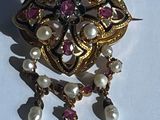 une broche en or ornée de perles, posée sur un fond blanc