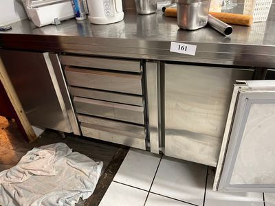 un plan de travail en acier inoxydable dans une cuisine professionnelle, avec une poubelle