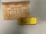 a piece of gold on the table next to a ticket