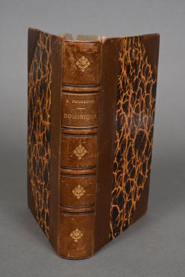 an old book with a brown cover sitting on top of a table